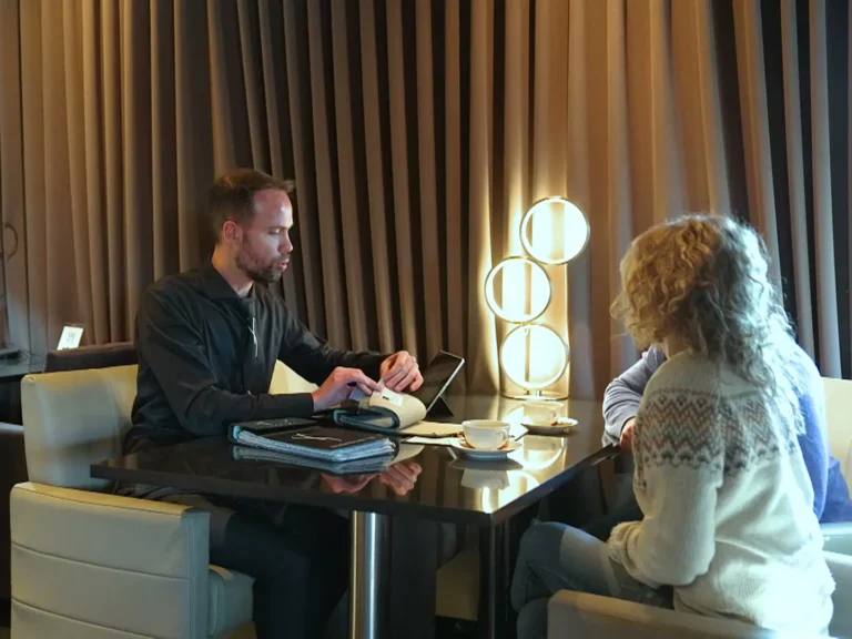Adviseur van T&T Design overloopt samen met een klant stalen en een catalogus aan een tafel in de showroom