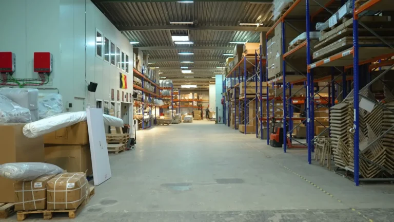 Brede, lichte gang door het magazijn met rekken, verpakte meubels en pallets
