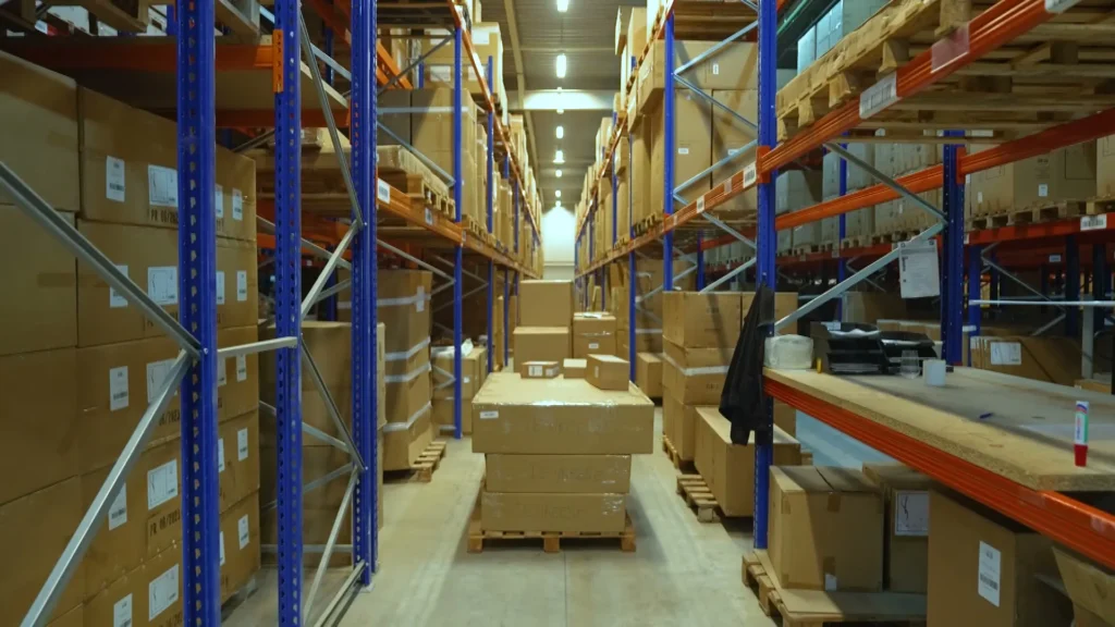 Lange gang tussen hoge palletrekken vol dozen in het magazijn