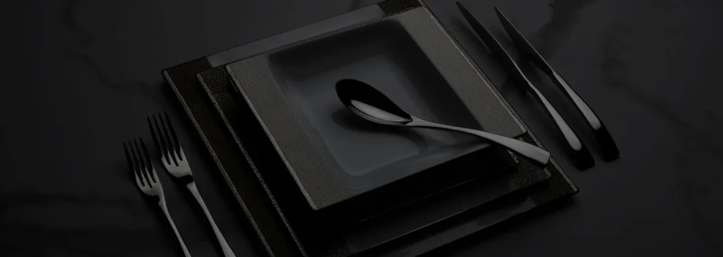 Zwart vierkant servies met zwarte lepel en bestek op een donkere ondergrond, sober en elegant